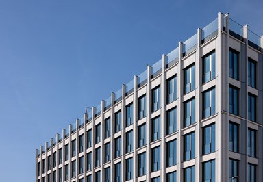 Die fein gegliederte Natursteinfassade von Bauteil 1 prägt mit ihrem regelmäßigen Raster und tiefen Fensterlaibungen die ruhige, hochwertige Erscheinung des Gebäudes. - © caspar./HGEsch